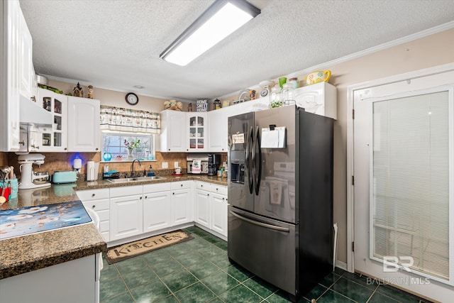 kitchen featuring white cabinets, glass insert cabinets, stainless steel fridge, and a sink