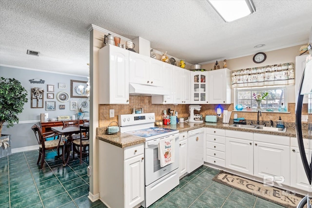 kitchen with white appliances, dark tile patterned flooring, ornamental molding, a sink, and under cabinet range hood