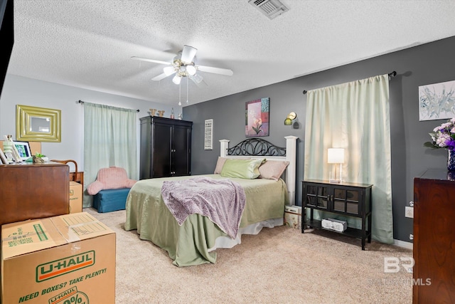 bedroom featuring visible vents, carpet floors, a textured ceiling, and ceiling fan