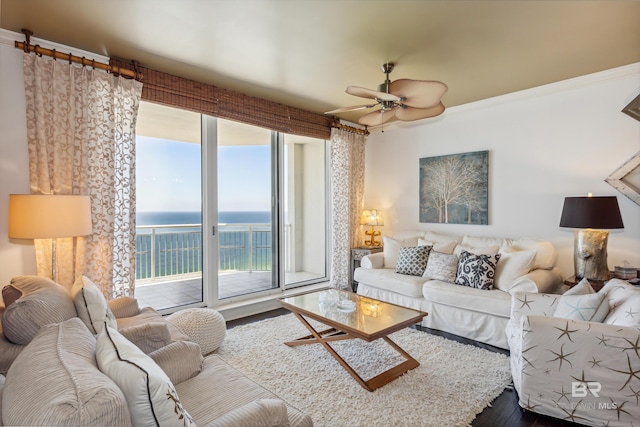 living room with ceiling fan, a water view, and hardwood / wood-style floors