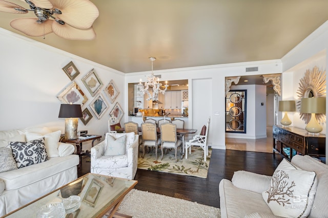 living room featuring a notable chandelier, dark hardwood / wood-style flooring, and crown molding