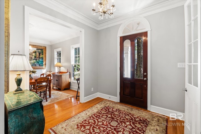 foyer entrance featuring wood-type flooring, crown molding, and an inviting chandelier