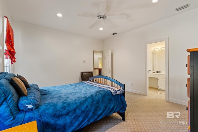 bedroom featuring ceiling fan, light colored carpet, and connected bathroom