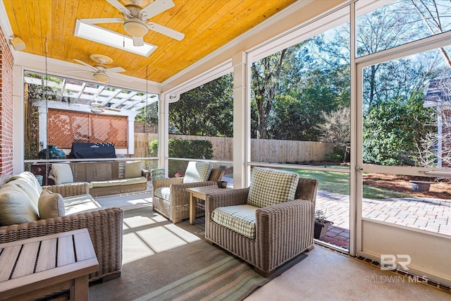 sunroom featuring a skylight, ceiling fan, and wood ceiling