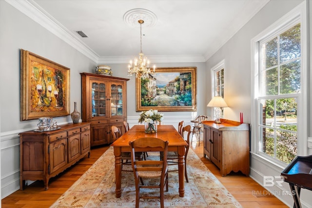 dining space featuring a chandelier, ornamental molding, and light hardwood / wood-style flooring