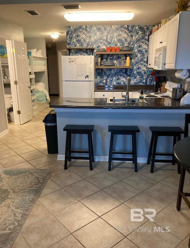 kitchen featuring a kitchen breakfast bar, white cabinetry, white appliances, and kitchen peninsula