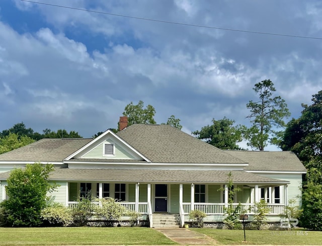 farmhouse inspired home with a front lawn, a porch, a chimney, and a shingled roof