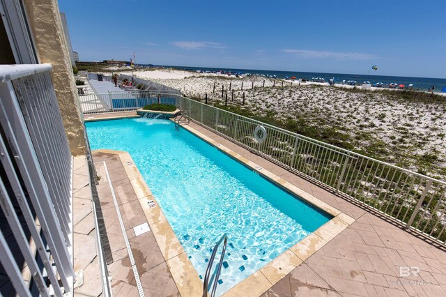 view of swimming pool with a water view and a view of the beach