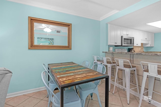 dining space featuring ceiling fan, light tile patterned flooring, sink, and crown molding