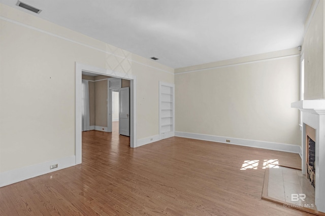 1706 Hunter Ave, Mobile, AL 36604 - unfurnished living room with a fireplace, light wood-style floors, and built in shelves