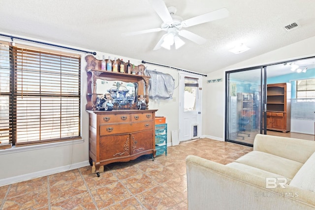 living room featuring ceiling fan, lofted ceiling, and a textured ceiling