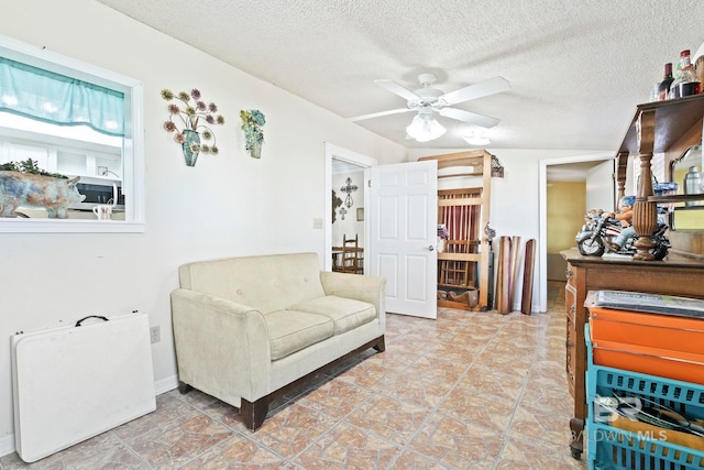 living area with ceiling fan and a textured ceiling