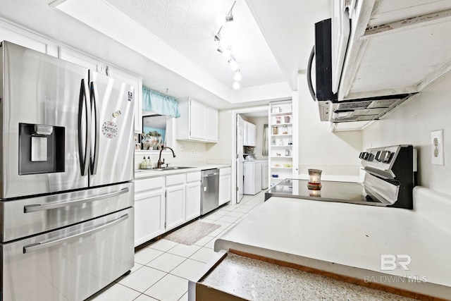 kitchen featuring washer and clothes dryer, white cabinetry, stainless steel appliances, and light tile patterned floors