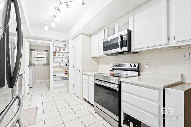 kitchen featuring a raised ceiling, white cabinetry, light tile patterned floors, and appliances with stainless steel finishes