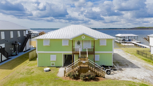 view of front of home with metal roof, a water view, driveway, stairway, and a front yard