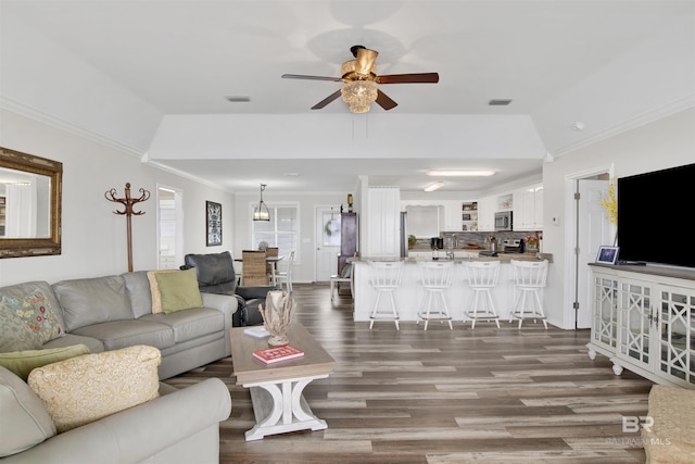 living room with visible vents, dark wood finished floors, a ceiling fan, and ornamental molding