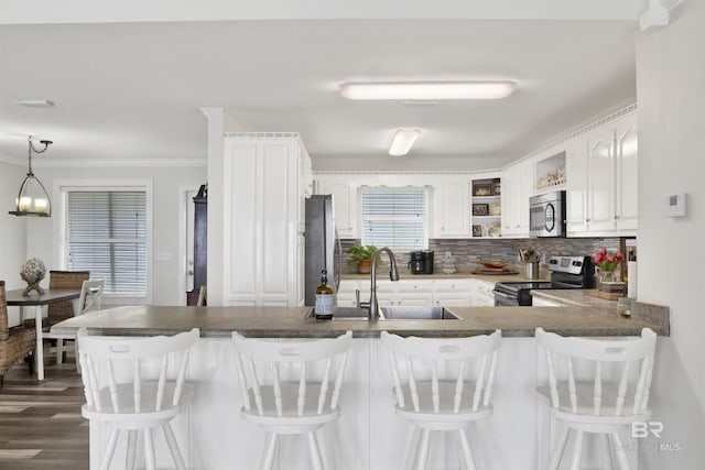 kitchen with open shelves, decorative backsplash, appliances with stainless steel finishes, a sink, and a peninsula