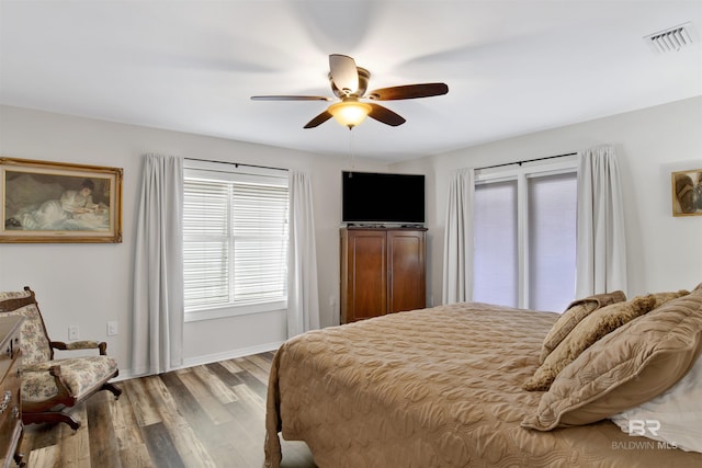 bedroom with baseboards, wood finished floors, visible vents, and a ceiling fan