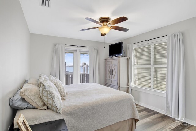 bedroom featuring a ceiling fan, baseboards, visible vents, and wood finished floors