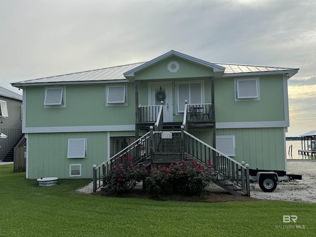 view of front of house featuring metal roof, covered porch, stairs, a standing seam roof, and a front yard