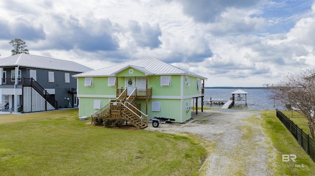 exterior space featuring a water view, a lawn, stairway, and fence