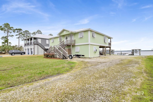 view of front facade featuring a carport, driveway, a front lawn, and stairs