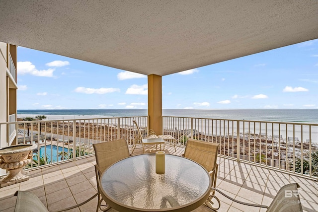 balcony with a water view, a beach view, and a patio area