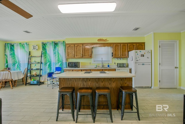 8239 Gulf Beach Ln, Gulf Shores, AL 36542 - kitchen with a sink, white appliances, light countertops, brown cabinetry, and visible vents