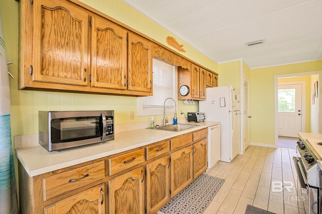 8239 Gulf Beach Ln, Gulf Shores, AL 36542 - kitchen featuring appliances with stainless steel finishes, a sink, light countertops, brown cabinetry, and visible vents