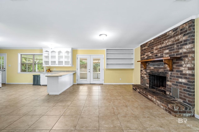 kitchen with light tile patterned floors, a fireplace, ornamental molding, white cabinets, and french doors