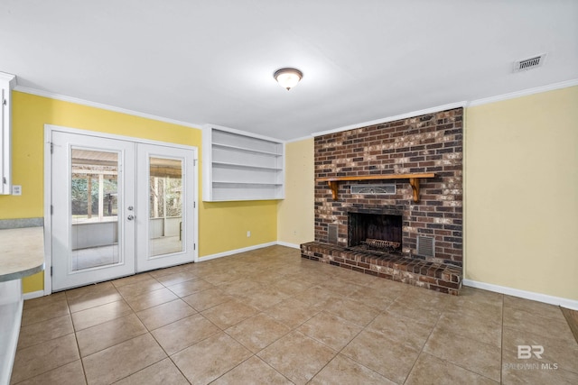 unfurnished living room with crown molding, light tile patterned floors, a brick fireplace, and french doors