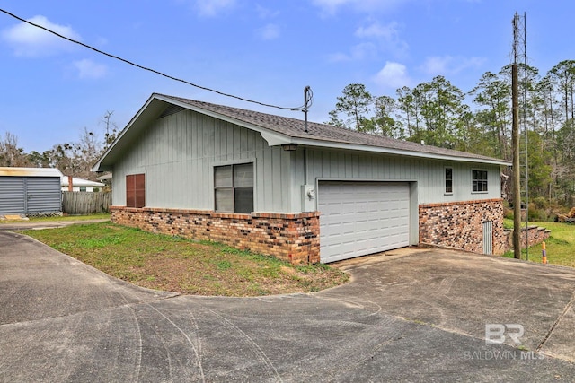 exterior space with a garage, fence, aphalt driveway, and brick siding