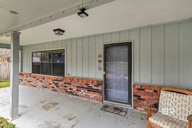 view of exterior entry featuring board and batten siding and brick siding