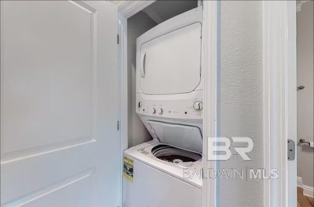 laundry area with stacked washing maching and dryer, laundry area, and a textured wall