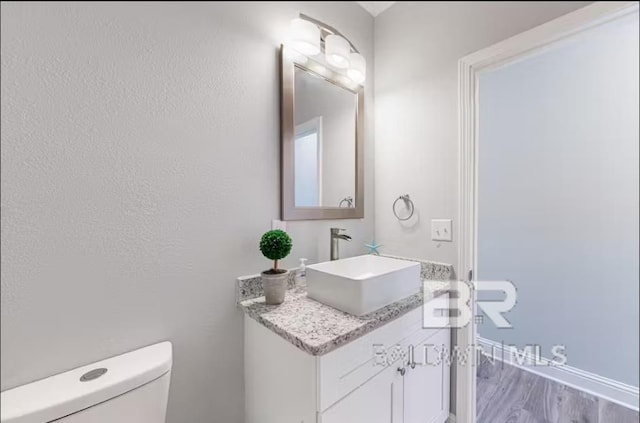 bathroom featuring wood finished floors, vanity, and toilet