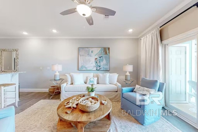 living area featuring ornamental molding, a ceiling fan, baseboards, and wood finished floors