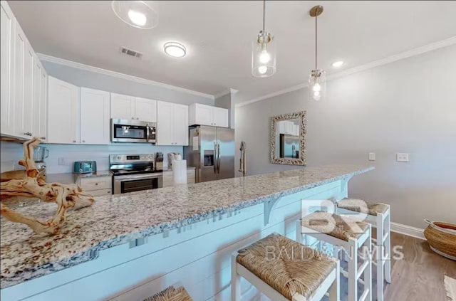 kitchen featuring light stone counters, stainless steel appliances, a peninsula, visible vents, and crown molding