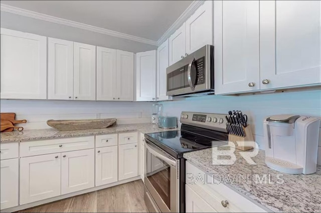 kitchen featuring light wood finished floors, white cabinets, light stone countertops, stainless steel appliances, and crown molding