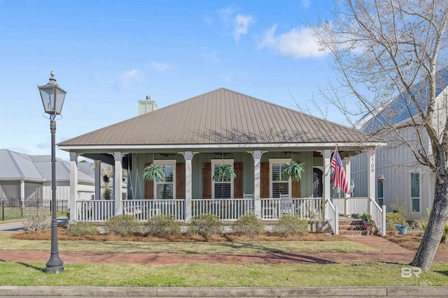 view of front of property with a chimney, a porch, and metal roof