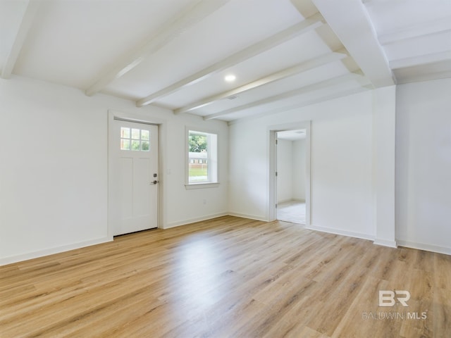 spare room with light wood-type flooring and beamed ceiling