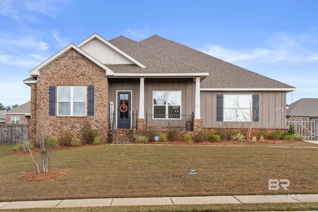 view of front of home with a front yard, brick siding, board and batten siding, and a shingled roof