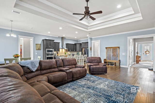 living room with visible vents, a raised ceiling, ornamental molding, baseboards, and dark wood-style flooring