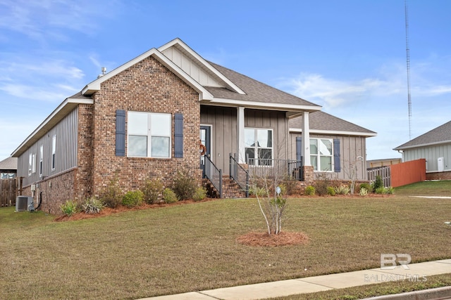 view of front of home featuring cooling unit, brick siding, board and batten siding, and a front lawn