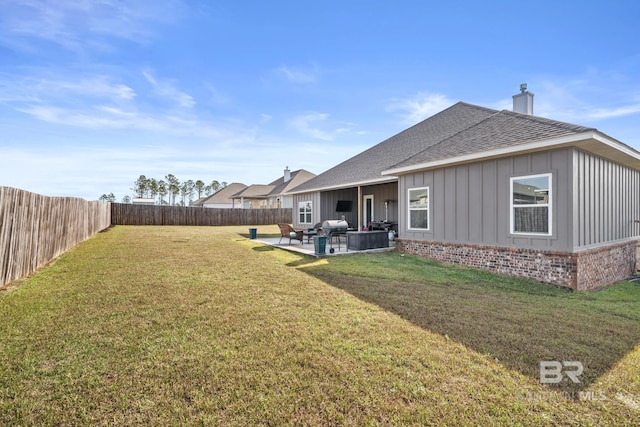 rear view of house with a fenced backyard, a yard, roof with shingles, board and batten siding, and a patio area