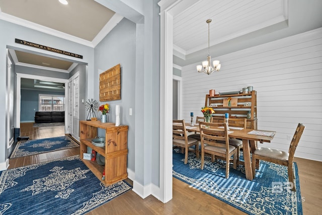 dining area featuring ornamental molding, wood finished floors, baseboards, and a chandelier