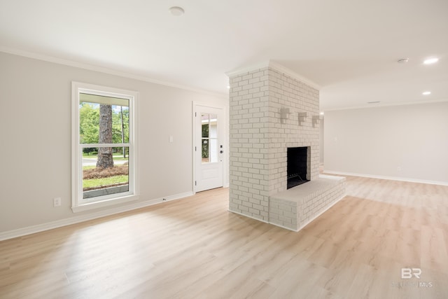 unfurnished living room featuring light wood-type flooring, a brick fireplace, and ornamental molding