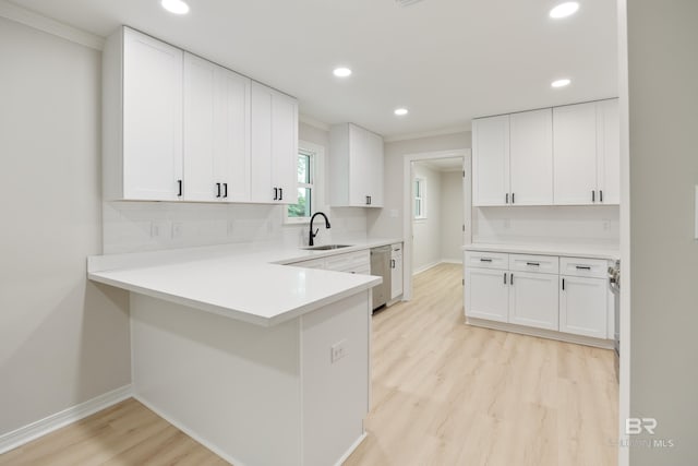 kitchen with dishwasher, sink, kitchen peninsula, light hardwood / wood-style floors, and white cabinetry