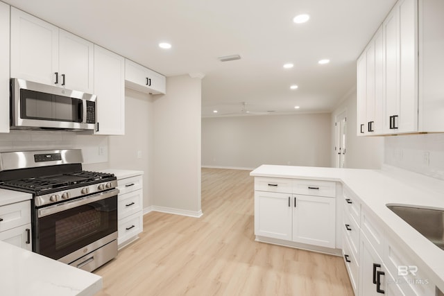 kitchen featuring white cabinets, light wood-type flooring, stainless steel appliances, and backsplash