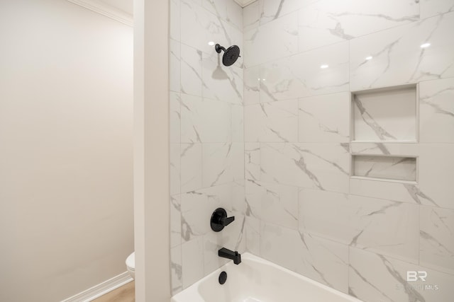 bathroom featuring tiled shower / bath combo and toilet