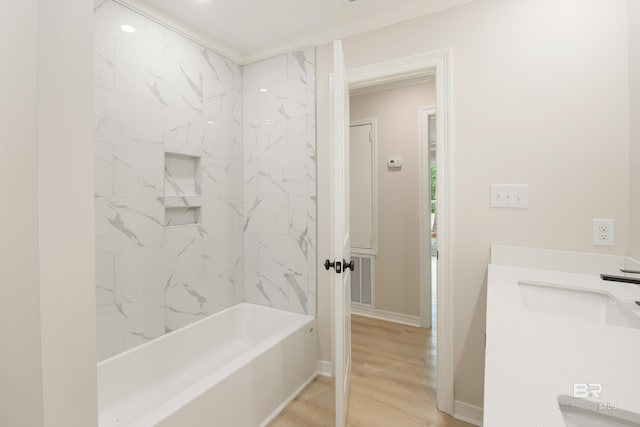 bathroom featuring wood-type flooring, vanity, tiled shower / bath, and crown molding